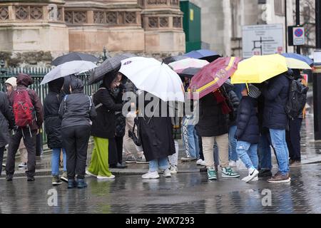 In Westminster, London, sind die Menschen vor dem Regen geschützt. Laut Wettervorhersage bewegt sich ein Gebiet mit Regen, Schneeregen und Bergschnee nach Norden durch Großbritannien, während sich Urlauber auf Osterausflüge vorbereiten. Bilddatum: Donnerstag, 28. März 2024. Stockfoto