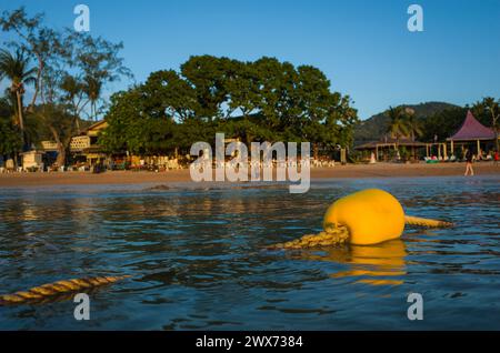 Gelbe Schwimmboje aus Kunststoff auf dickem Seil im ruhigen Wasser mit Blick auf die tropische Insel Koh Tao, Sairee Beach, Thailand. Abends Stockfoto