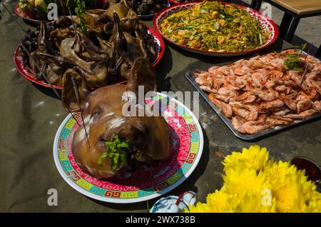 Großer gekochter Schweinekopf auf Teller auf dem Tisch unter anderen Gerichten Opfergaben für Gott beim chinesischen Neujahrsfest auf Koh Tao Insel, Thailand Stockfoto