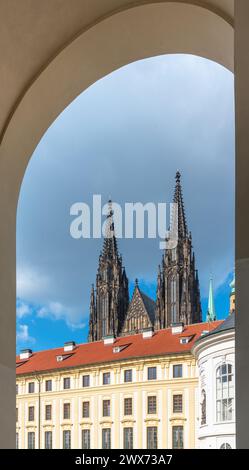 Die Zwillingsspitzen der St. Der Vitusdom erhebt sich majestätisch über der Prager Burg, eingerahmt von einem Bogengang unter einem bewölkten Himmel. Prag, Tschechien Stockfoto