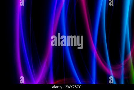 Abstrakte bunte unregelmäßige Linien auf schwarzem Hintergrund und Wandstruktur. Lange Belichtung. Lichtmalerei. Stockfoto