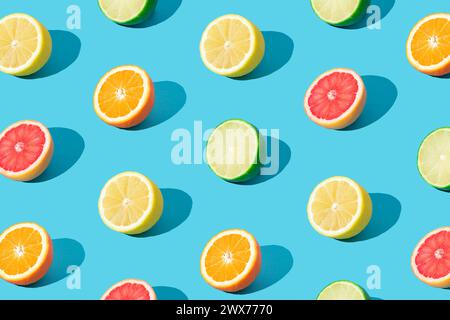 Buntes Sonnenlicht-Fruchtmuster aus roten Grapefruit-, Orange-, Limetten- und Zitronenscheiben auf hellblauem Hintergrund. Minimales Sommerkonzept. Kreatives Essen Stockfoto