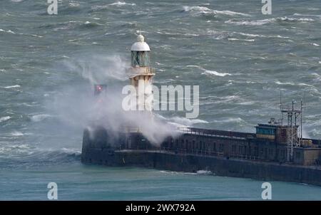 Wellen stürzen über einen Leuchtturm an der Hafenmauer in Dover, Kent. Laut Wettervorhersage bewegt sich ein Gebiet mit Regen, Schneeregen und Bergschnee nach Norden durch Großbritannien, während sich Urlauber auf Osterausflüge vorbereiten. Bilddatum: Donnerstag, 28. März 2024. Stockfoto