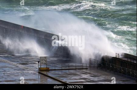 Wellen krachen über die Hafenmauer in Dover, Kent. Laut Wettervorhersage bewegt sich ein Gebiet mit Regen, Schneeregen und Bergschnee nach Norden durch Großbritannien, während sich Urlauber auf Osterausflüge vorbereiten. Bilddatum: Donnerstag, 28. März 2024. Stockfoto