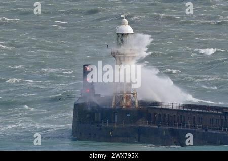 Wellen stürzen über einen Leuchtturm an der Hafenmauer in Dover, Kent. Laut Wettervorhersage bewegt sich ein Gebiet mit Regen, Schneeregen und Bergschnee nach Norden durch Großbritannien, während sich Urlauber auf Osterausflüge vorbereiten. Bilddatum: Donnerstag, 28. März 2024. Stockfoto