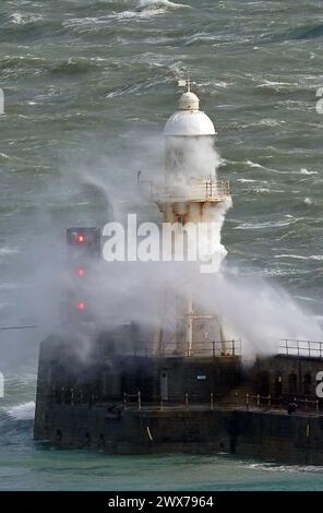 Wellen stürzen über einen Leuchtturm an der Hafenmauer in Dover, Kent. Laut Wettervorhersage bewegt sich ein Gebiet mit Regen, Schneeregen und Bergschnee nach Norden durch Großbritannien, während sich Urlauber auf Osterausflüge vorbereiten. Bilddatum: Donnerstag, 28. März 2024. Stockfoto