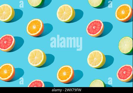 Buntes Sonnenlicht-Fruchtmuster aus roten Grapefruit-, Orange-, Limetten- und Zitronenscheiben auf hellblauem Hintergrund mit Kopierraum. Minimales Sommerkonzept Stockfoto