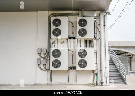 Klimaanlagen-Verflüssigungseinheit an der Wand an der Außentür zur Wärmebelüftung des Kühlsystems in der Nähe der Treppe installieren. Stockfoto