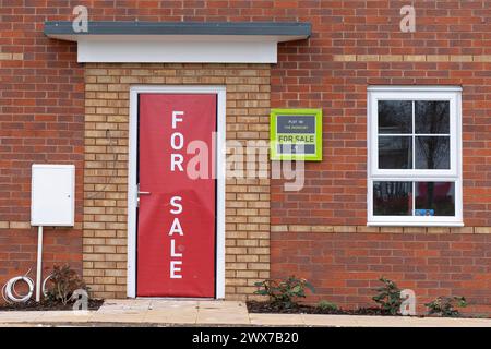 Nahaufnahme eines „for Sale“-Schilds, das die gesamte Eingangstür eines neu erbauten Wohnhauses/Hauses auf britischem Gebiet (Barratt Homes) abdeckt. Stockfoto