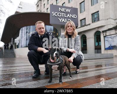 Staffie überquert Stella mit ihren neuen Besitzern, dem Polizisten Joe Allen und dem Polizisten Jade Peirce, im New Scotland Yard, Zentrum von London. PC Allen und DC Peirce adoptierten Stella, nachdem sie im Dezember in Tottenham, Nord-London, verlassen, extrem unterernährt und medizinisch versorgt worden war. Bilddatum: Donnerstag, 28. März 2024. Stockfoto