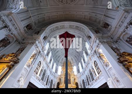 München, Deutschland. März 2024. Ein rotes Tuch bedeckt das Kreuz vor dem Altar in St. Michaels Kirche. In vielen Kirchen werden im Vorfeld von Ostern Jesu Darstellungen verschleiert, um dann am Karfreitag in einem Gottesdienst wieder feierlich enthüllt zu werden. Quelle: Sven Hoppe/dpa/Alamy Live News Stockfoto