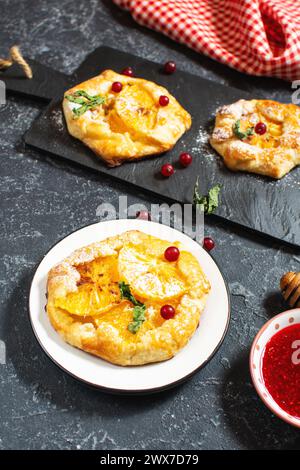Süßer Kuchen mit orangefarbenen karamelisierten Scheiben auf schwarzem Steinhintergrund. Stockfoto