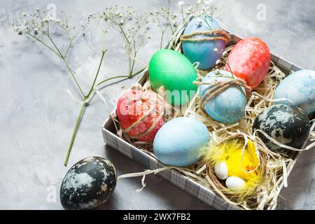 Frohe Ostern. Natürlich gefärbte, bunte Eier in Papiertablett auf Betonplatte im rustikalen Stil. Stimmungsvolles Bild Stockfoto