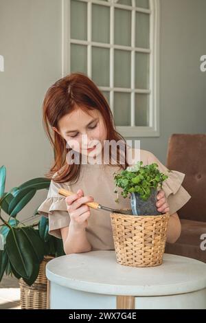 Ein kleines Mädchen, das Samen in die Töpfe pflanzt. Kinderhilfe bei der Pflege von Heimpflanzen. Heimgärtnern, Pflanzen Pflanzen Pflanzen Pflanzen Pflanzen, Setzlinge Stockfoto