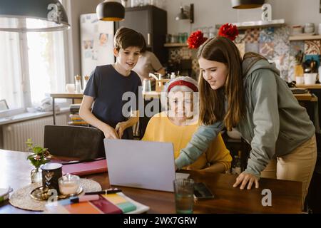 Mädchen, das mit Großmutter und Bruder zu Hause einen Laptop benutzt Stockfoto