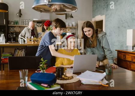 Geschwister helfen Großmutter mit einem Laptop zu Hause auf dem Tisch Stockfoto