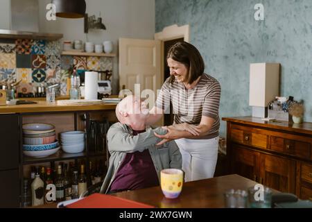 Glückliche Frau, die den älteren Schwiegervater zu Hause begrüßt Stockfoto