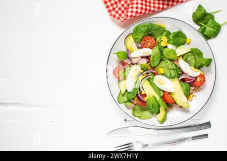 Thunfischsalat - Thunfisch, Avocado, hart gekochte Eier, Kirschtomaten, Salat und Zwiebeln auf Holztisch. Gesunde Ernährung Stockfoto