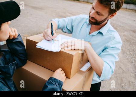 Hochwinkelansicht eines Mannes, der Papiere beim Empfang des Pakets vom Zusteller ausführt Stockfoto