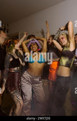 Eine Gruppe fröhlicher, nicht-binärer Freunde, die zusammen im Nachtclub tanzen Stockfoto