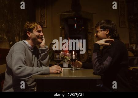 Glückliches, junges schwules Paar, das bei Kerzenlicht bei Kerzenschein an der Bar saß Stockfoto