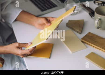 Hände einer Architektin, die Farbmuster beim Sitzen am Schreibtisch im Büro vergleicht Stockfoto