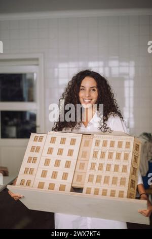 Porträt einer lächelnden Architektin, die im Büro ein Modell hält Stockfoto