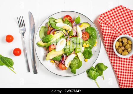 Thunfischsalat - Thunfisch, Avocado, hart gekochte Eier, Kirschtomaten, Salat und Zwiebeln auf Holztisch. Gesunde Ernährung Stockfoto