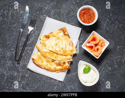 Russische dünne Pfannkuchen oder Blini mit rotem Kaviar und Lachs auf schwarzer Platte. Draufsicht. Stockfoto