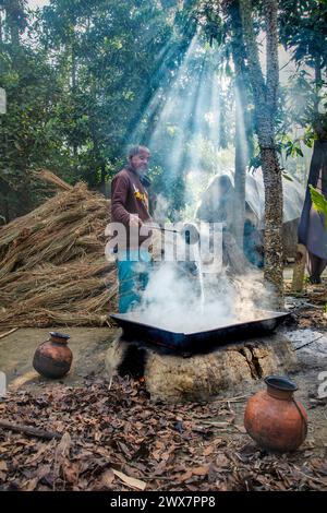 Ein alter Mann macht Melasse, indem er Dattelsaft kocht, der von Dattelpalmen in einem großen Topf gesammelt wird. Im Winter wird der saft von Palmen und gesammelt Stockfoto