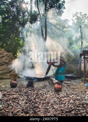 Ein alter Mann macht Melasse, indem er Dattelsaft kocht, der von Dattelpalmen in einem großen Topf gesammelt wird. Im Winter wird der saft von Palmen und gesammelt Stockfoto