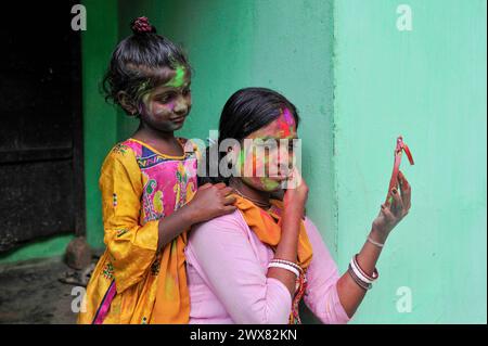 Sylhet, Bangladesch. März 2024. 26. März 2024, Sylhet, Bangladesch: Ein Mädchen mit gemaltem Gesicht sieht aus, als ihre Mutter ihr Gesicht mit farbigem Puder malt, um das jährliche Hindufest der Farben zu feiern, bekannt als Holi Festival, das den Beginn des Frühlings markiert. Am 26. März 2024 in Sylhet, Bangladesch. (Foto: MD Rafayat Haque Khan/Eyepix Group/SIPA USA) Credit: SIPA USA/Alamy Live News Stockfoto