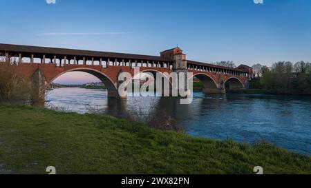 Wunderschöne Aussicht auf Ponte Coperto (überdachte Brücke) ist eine Brücke über den Tessin Fluss in Pavia bei Sonnenuntergang, Lombardei, Pavia, Italien Stockfoto