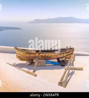 Das schäbige alte Ruderboot wird verwendet, um den Bereich vor einer Wohnung mit Blick auf die Caldera Santorin und die Ägäis zu dekorieren Stockfoto