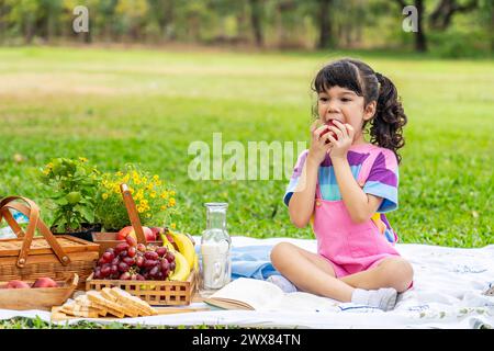 Ein junges Mädchen auf Decke im Park, das Apfel genießt Stockfoto