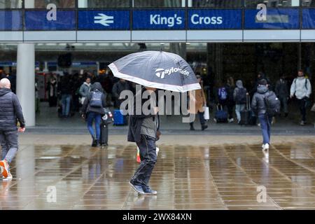 Ein Mann versteckt sich unter einem Schirm während des Regenfalls im Zentrum Londons. Stockfoto