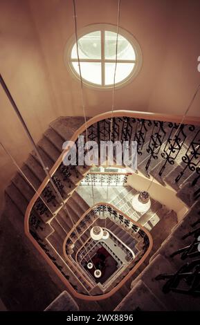 Wendeltreppe im Turm - Blick von oben. Perspektivischer Blick auf eine quadratische Treppe in einem alten Haus. Das Innere des Turms ist orange-braun. Stockfoto