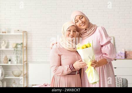 Muslimische Erwachsene Frau mit Mutter und Tulpenstrauß zu Hause. Internationaler Frauentag Stockfoto