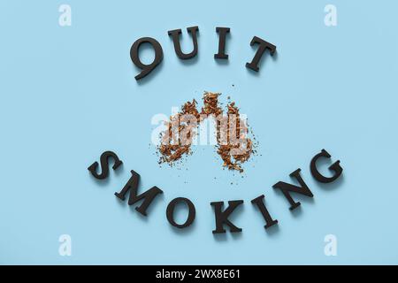 Hölzerner Satz VERZICHTET AUF DAS RAUCHEN und verstreut Tabak in Form von Lungen auf blauem Hintergrund. Rauchverbot Stockfoto