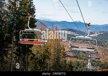 Leere Stühle an einem Skilift an einem sonnigen Tag auf einer verschneiten Piste. Freizeit Stockfoto