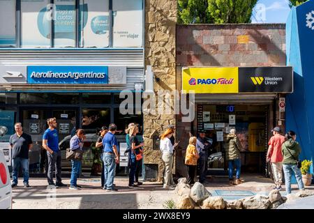 Personen, die sich vor Einem Büro von Pago Facil/Western Union in El Calafate, Patagonien, Argentinien, in Warteschlangen befinden. Stockfoto