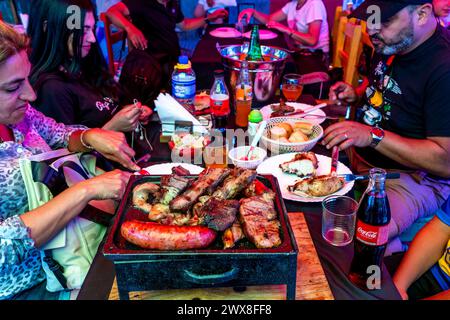 Menschen, die Ein traditionelles Asado/Barbecue-Essen In Einem Restaurant im La Boca-Viertel von Buenos Aires, Argentinien, essen. Stockfoto