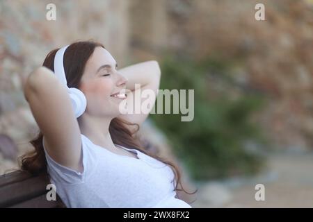 Entspannte und glückliche Frau, die mit Kopfhörern Musik hört Stockfoto