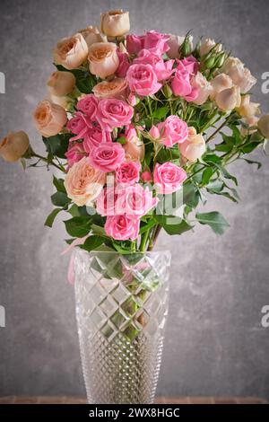 Strauß aus rosa und weißen Rosen in Vase auf grauem Hintergrund Stockfoto