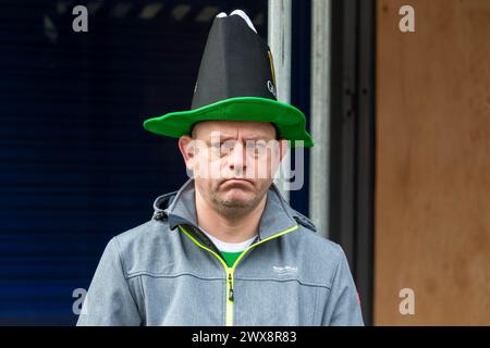 Unglücklicher Mann mit Guinness-Hut steht allein und beobachtet die Parade Stockfoto