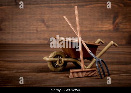 Miniatur-Rasenmäher und Gartenwerkzeuge auf Holztextur Hintergrund. Stockfoto