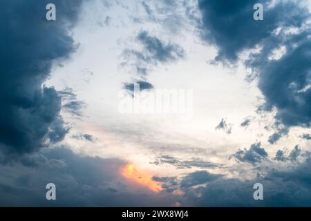 Das Bild fängt einen ruhigen Sonnenuntergang ein, bei dem ein orangefarbenes Licht durch den bewölkten Schleier bricht Stockfoto