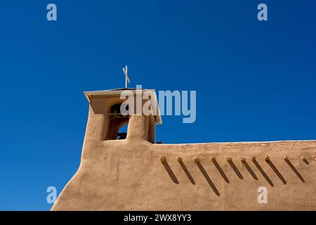 Lehmwände und Glockenturm mit freiliegenden Viga-Dachbalken der San Francisco de Assisi Missionskirche in Taos, New Mexico Stockfoto