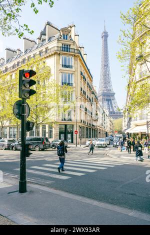 Fußgänger laufen an klaren Tagen in der Nähe einer Straßenecke mit dem Eiffelturm im Hintergrund. Paris, Frankreich Stockfoto