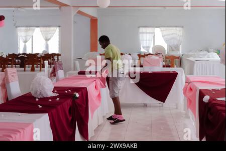 Eine Frau, die Einen Speisesaal für einen Hochzeitsempfang in Yardley Chase, St. Elizabeth in Jamaika vorbereitet Stockfoto